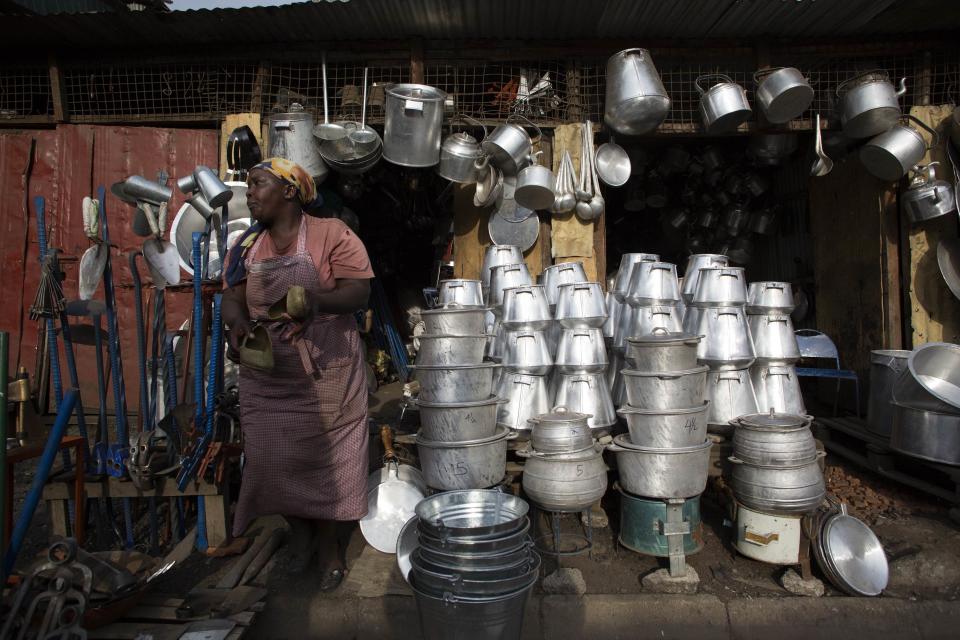 Una mujer se encuentra en una tienda local que vende platos y otros utensilios hechos de metal reciclado procedente de los barriles viejos en Kamukunji, Nairobi.