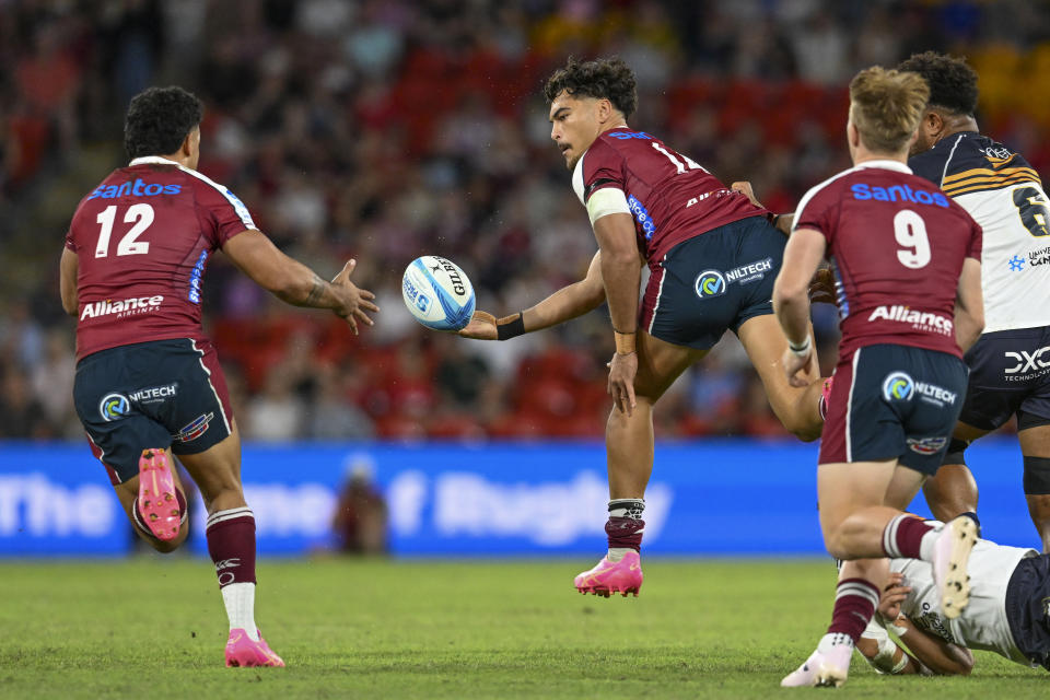 Jordan Petaia of the Reds passes to teammate Hunter Paisami, left, during the Super Rugby match between the Queensland Reds and the Brumbies in Brisbane, Australia, Saturday, March 30, 2024. (Darren EnglandAAP via AP)