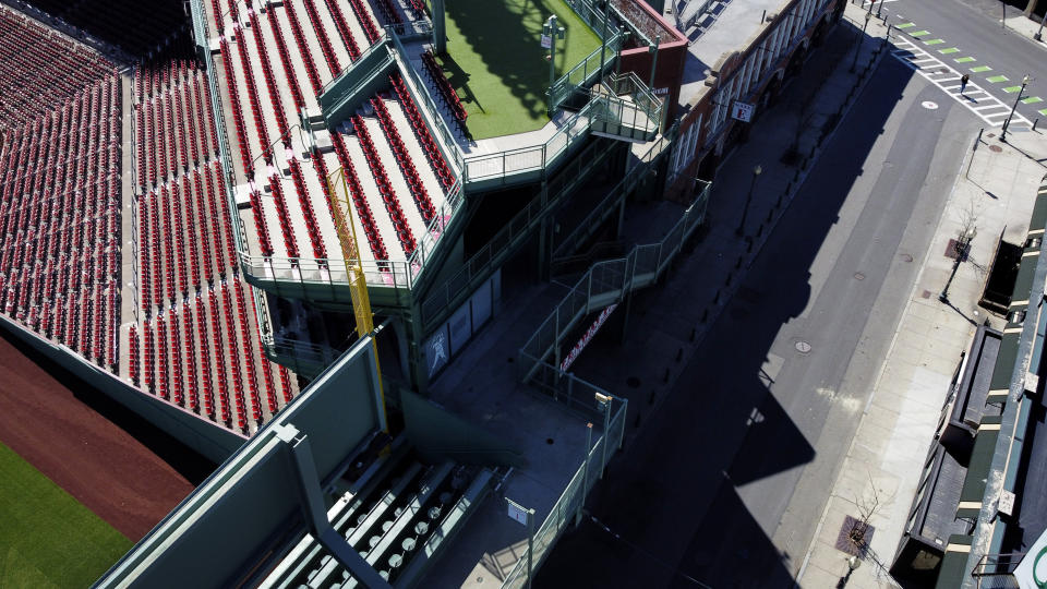 A sole pedestrian crosses Lansdowne Street which would normally be bustling with Boston Red Sox baseball fans watching the team's first game of the season being played in Toronto on Opening Day at bars around Fenway Park, Thursday, March 26, 2020, in Boston. This year's baseball season has been postponed in an effort to slow the spread of coronavirus. (AP Photo/David Goldman)