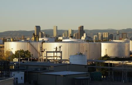 Oil storage tanks are seen at sunrise with the Rocky Mountains and the Denver downtown skyline in the background October 14, 2014. REUTERS/Rick Wilking