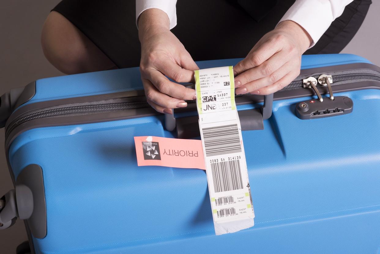 airline check in luggage tag being attached to a suitcase