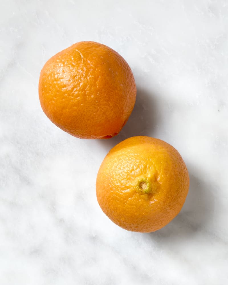 overhead shot of two mandarins on a white marble surface.