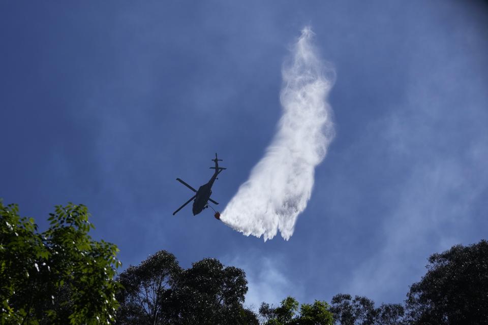 Un helicóptero rocía agua sobre un incendio forestal en las montañas que rodean Bogotá, Colombia, el martes 23 de enero de 2024. (AP Foto/Fernando Vergara)