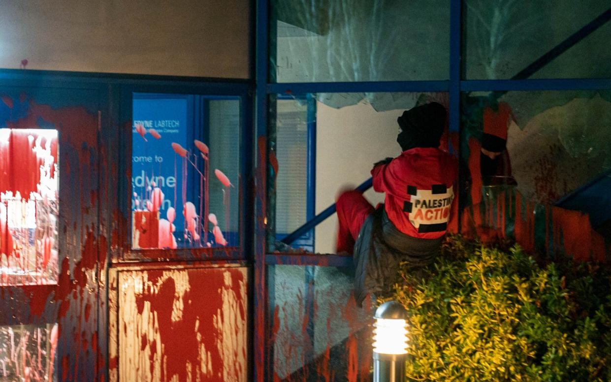 An activist climbs through a broken window at the Teledyne Technologies plant in Presteigne - Vladimir Morozov