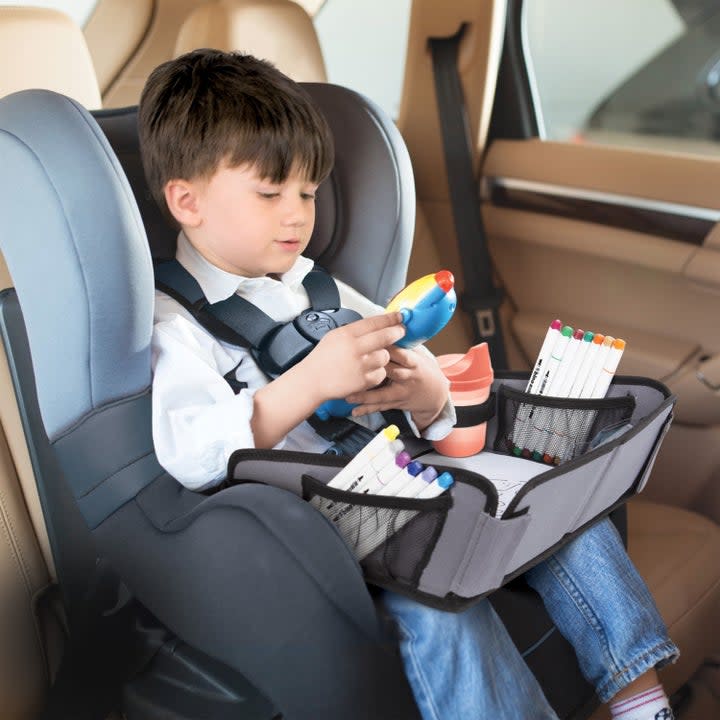 Child plays with a tray in a carseat