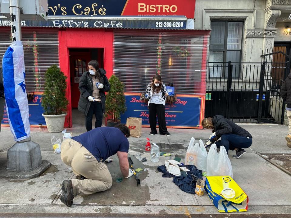 Cafe supporters work to remove the offensive graffiti. Melanie Notkin for the NYPost