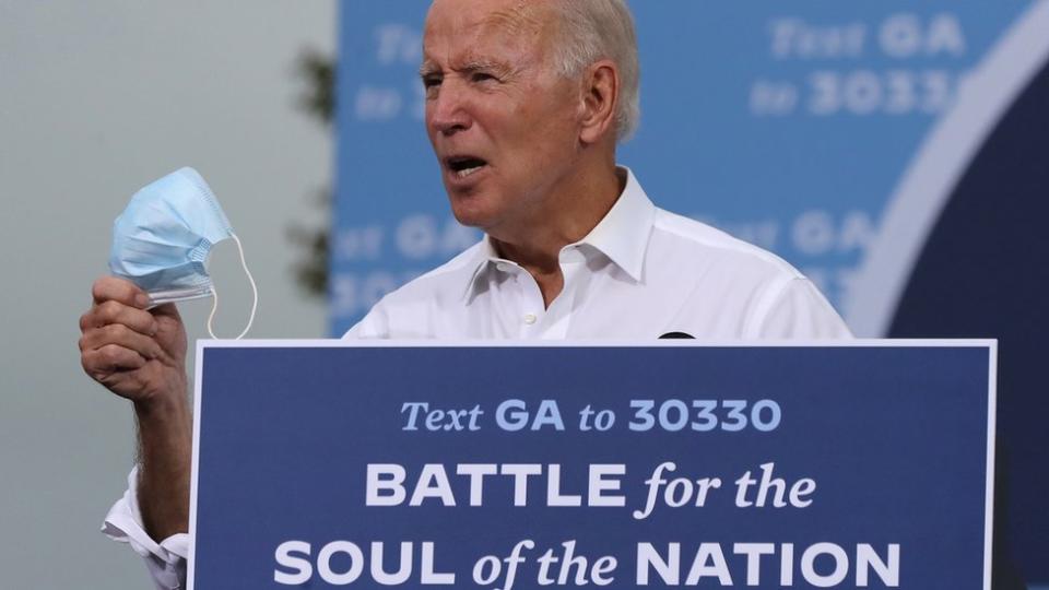 joe Biden con una mascarilla en la mano