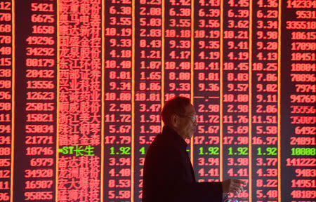 A man is seen in front of an electronic board showing stock information on the first day of trading in the Year of the Pig, following the Chinese Lunar New Year holiday, at a brokerage house in Hangzhou, Zhejiang province, China February 11, 2019. REUTERS/Stringer