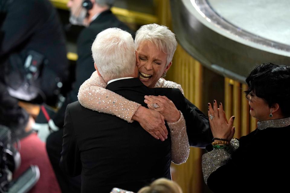 Jamie Lee Curtis hugs her husband, Christopher Guest, before accepting her Oscar for best actress in a supporting role for her performance in "Everything Everywhere All at Once" during the 95th Academy Awards on Sunday, March 12, 2023.