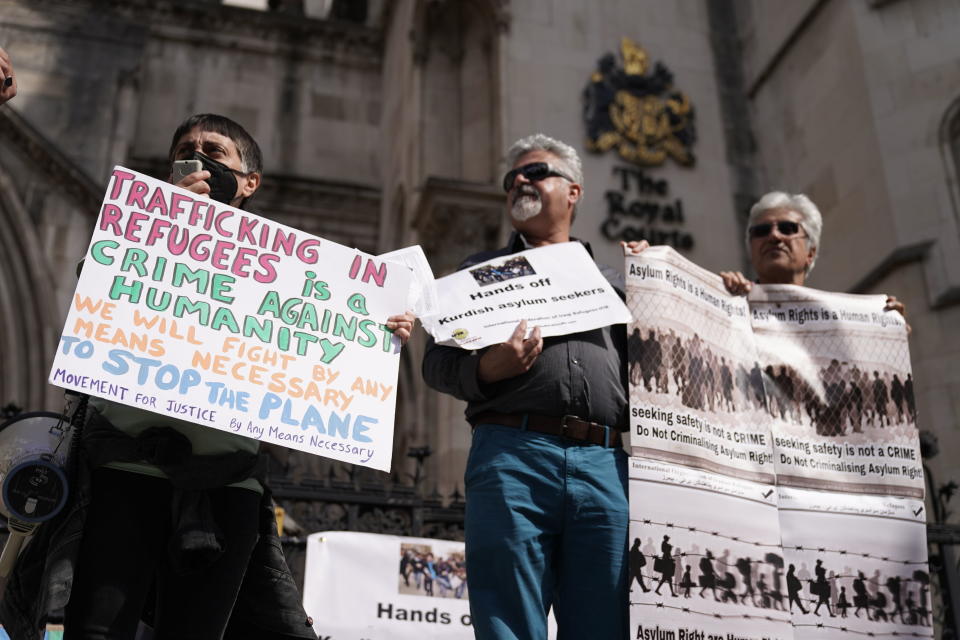 Protesters stand outside the High Court where the ruling on Rwanda deportation flights is taking place, in London Monday, June 13, 2022. Opponents of the British government’s plan to deport migrants to Rwanda prepared for an appeals court hearing Monday amid the political backlash following reports that Prince Charles had privately described the policy as “appalling.” (Aaron Chown/PA via AP)