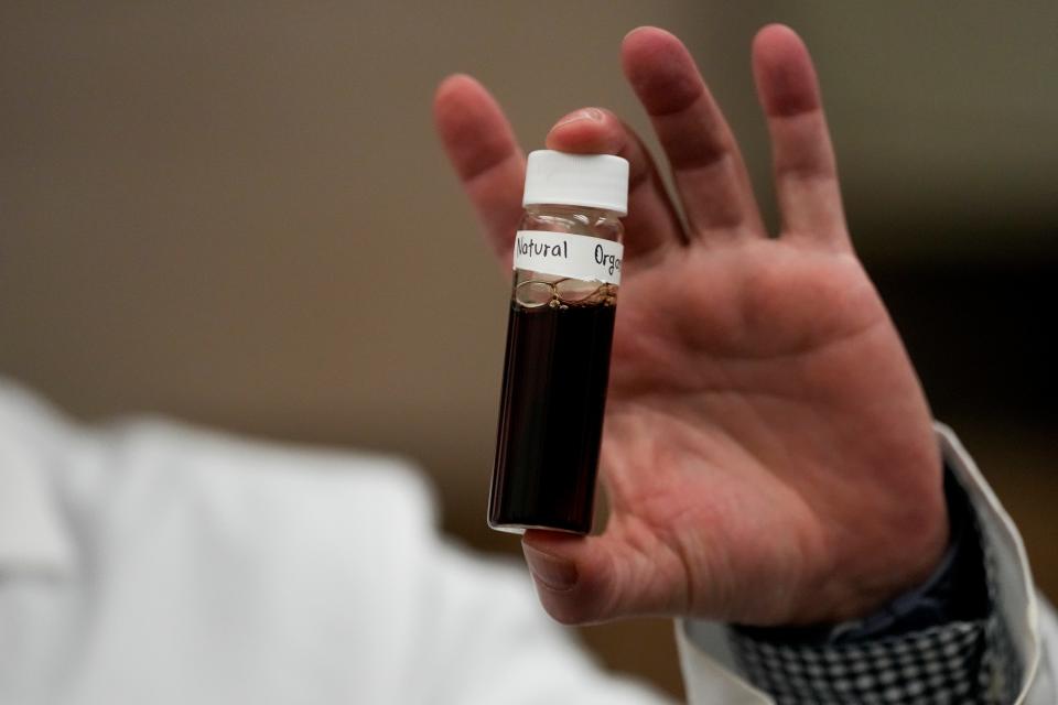 Jonathan Pressman holds a sample of natural organic matter used for testing in the Drinking Water Pilot Plant at the U.S. Environmental Protection Agency’s Andrew W. Breidenbach Environmental Research Center in Cincinnati on Tuesday, Feb. 14, 2023. The Drinking Water Pilot Plant conducts research with a focus on drinking water treatment technologies to remove contaminants, including PFAS.