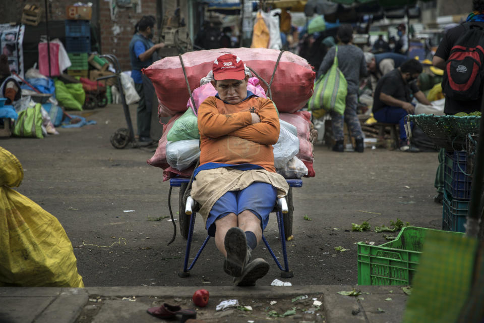 Porter Fernando Anaya, who begins his workday at 4 a.m., takes a nap as he takes a break from transporting vegetables, in La Parada market in La Victoria district, in Lima, Peru, Tuesday, June 23, 2020. With hundreds of millions relying on such markets for their food and livelihoods, officials are debating whether and how they can operate safely amid the new coronavirus pandemic. (AP Photo/Rodrigo Abd)