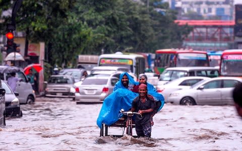 A Bangladeshi rickshaw puller makes his way through a water-logged street in Dhaka, Bangladesh - Credit: Munir Uz Zaman/AFP