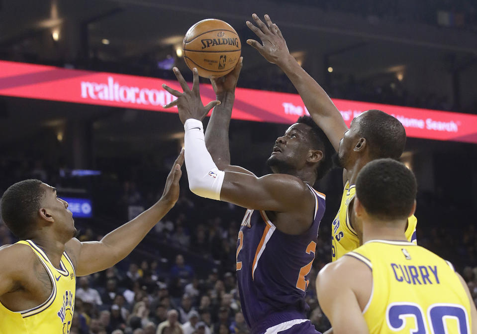 Phoenix Suns center Deandre Ayton, center, shoots between Golden State Warriors' Kevon Looney, left, Kevin Durant, top right, and Stephen Curry during the first half of an NBA basketball game in Oakland, Calif., Sunday, March 10, 2019. (AP Photo/Jeff Chiu)