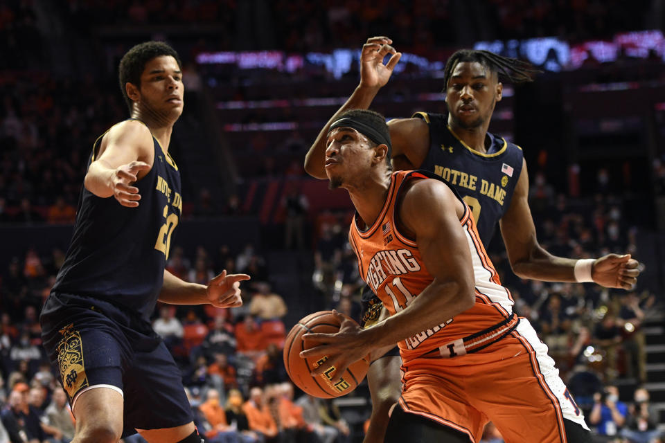 Illinois' Alfonso Plummer (11) attempts a layup as Notre Dame's Paul Atkinson Jr. (20) and Blake Wesley defend during the first half of an NCAA college basketball game Monday, Nov. 29, 2021, in Champaign, Ill. (AP Photo/Michael Allio)