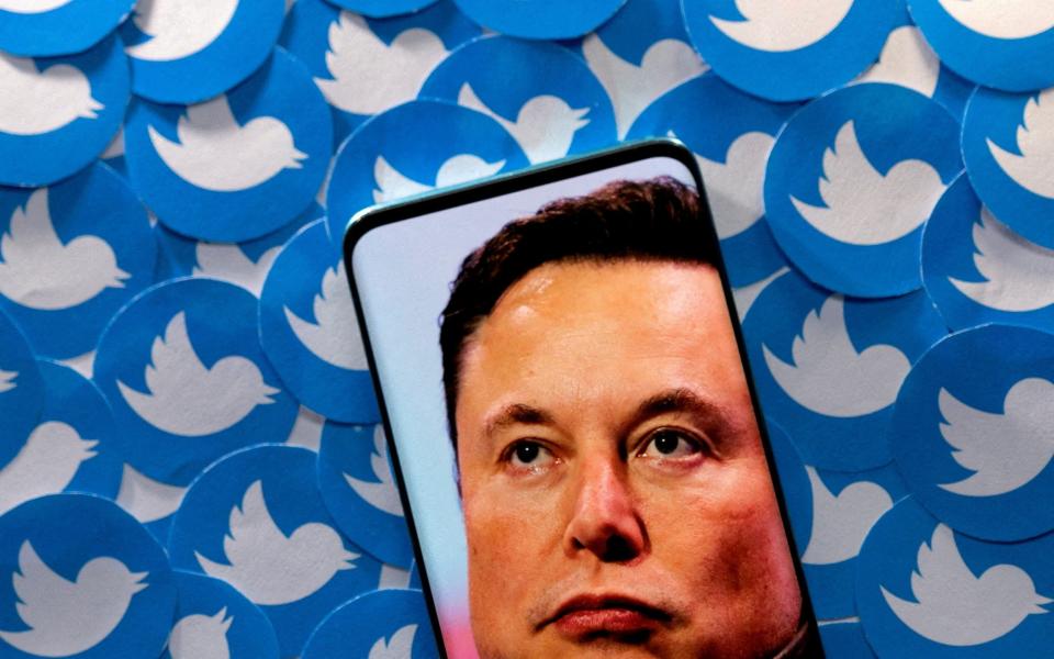 An image of Elon Musk is seen on a smartphone placed on printed Twitter logos in this picture illustration taken April 28, 2022. - DADO RUVIC/REUTERS