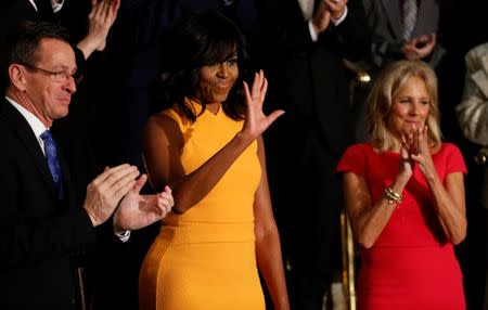 U.S. first lady Michelle Obama waves as she stands between Connecticut Governor Dannel Malloy (L) and Vice President Biden's wife Dr. Jill Biden (R) as they attend U.S. President Barack Obama's State of the Union address to a joint session of Congress in Washington, January 12, 2016. REUTERS/Jonathan Ernst
