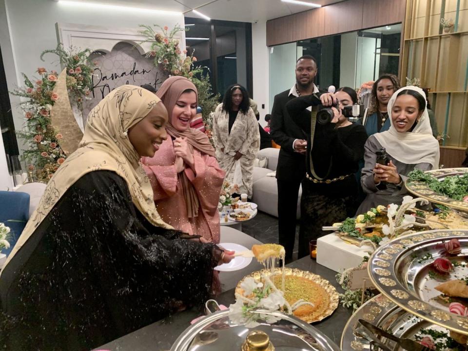 PHOTO: Influencer Aysha Harun cuts into this khafeh, a traditional Palestinian dessert, with the Knafeh Queen baker Fatmah Muhammad cheering her on as a photographer and videographer and influencers document the moment.  (ABC News)