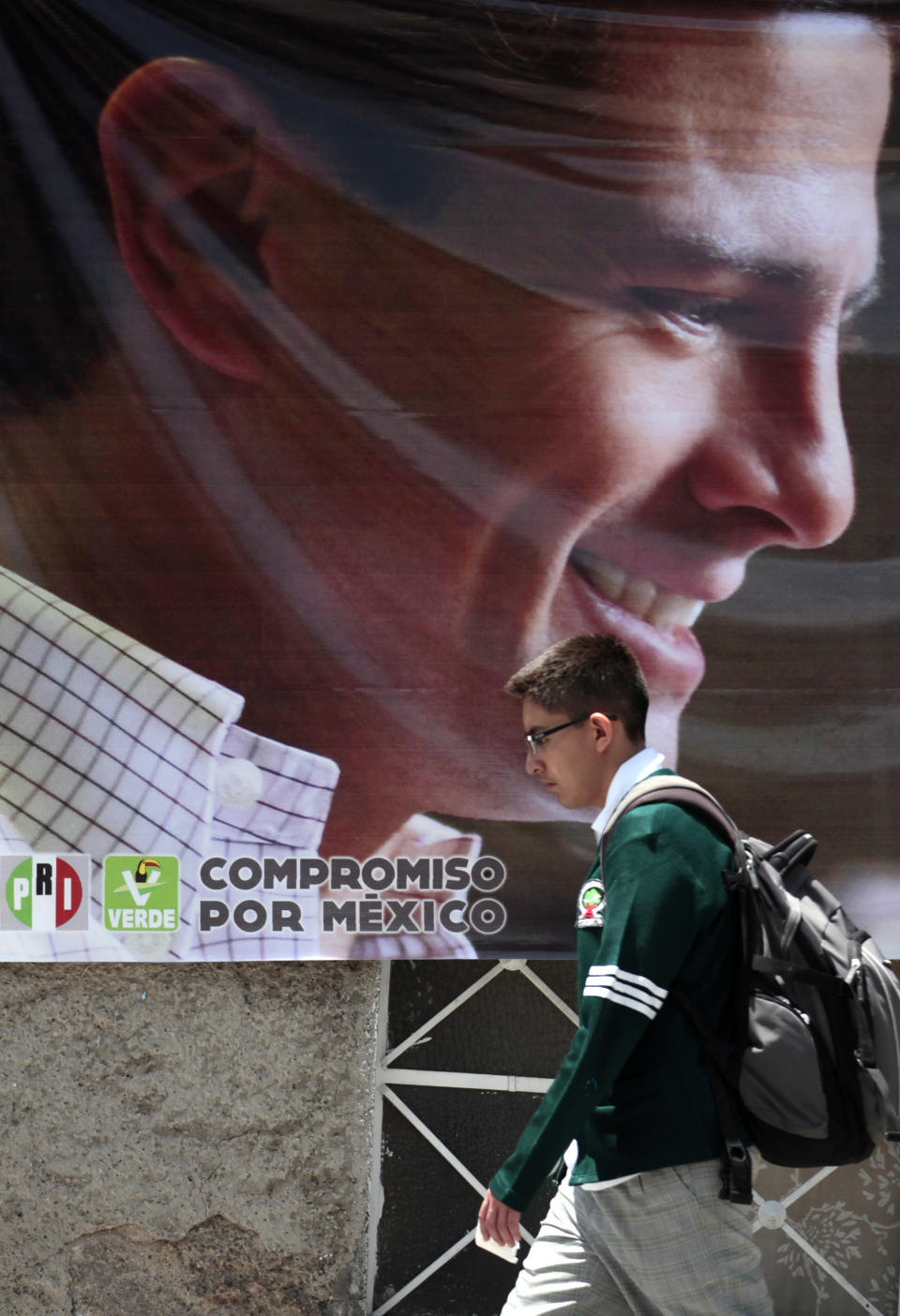 A student walks past an electoral banner with an image of Enrique Pena Nieto, presidential candidate of the opposition Institutional Revolutionary Party, PRI, in Mexico City, Monday, June 25, 2012. General elections in Mexico are scheduled for Sunday, July 1. (AP Photo/Esteban Felix)