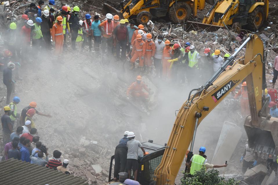 Rescue workers search for survivors in the rubble of a collapsed five-storey apartment building in Mahad. (Photo by PUNIT PARANJPE/AFP via Getty Images)