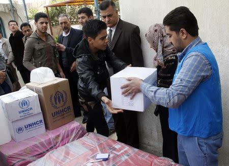 Displaced Iraqi Sunnis fleeing from Islamic State militants in al-Baghdadi district in Anbar provinces, receive aid from the United Nations Refugee Agency (UNHCR) in Baghdad February 24, 2015. REUTERS/Thaier Al-Sudani