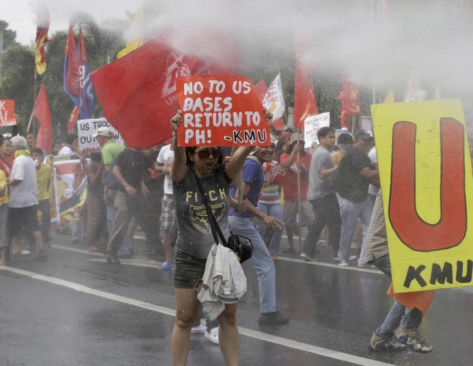 Firemen spray their water cannon at demonstrators as the latter force their way closer to U.S. Embassy in Manila, Philippines, Tuesday, Feb. 25, 2014 to protest the forthcoming visit of U.S. President Barack Obama. The protesters were also calling for the pullout of U.S. troops in the country under the Visiting Forces Agreement or VFA. (AP Photo/Bullit Marquez)