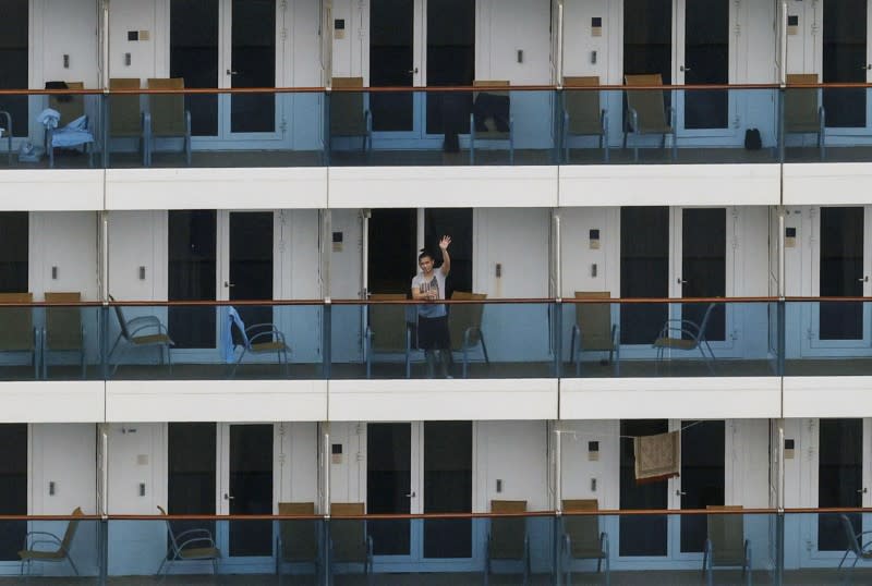 A crew member waves his hand on the balcony of Italian cruise ship Costa Atlantica, which has crew members confirmed with cases of the coronavirus disease (COVID-19) infection, in Nagasaki