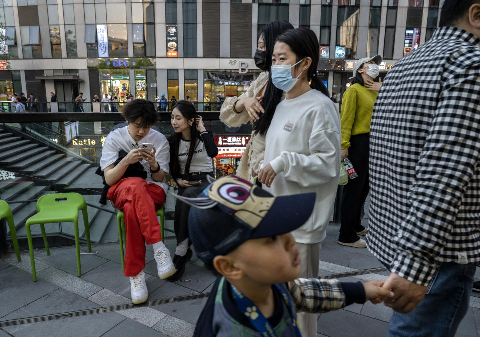 Customers, some wearing masks, look at a cell phone as they wait outside a restaurant for a table in a busy shopping area on April 18, 2023 in Beijing, China.  China's National Bureau of Statistics more than a year ago reported GDP growth of 4.5 percent in the first quarter of 2023, as the world's second-largest economy showed signs of growth after ending three years of strict zero measures earlier this year.  (Kevin Frayer/Getty Images)