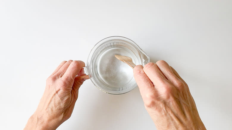 Dissolving sugar in warm water with wooden spoon