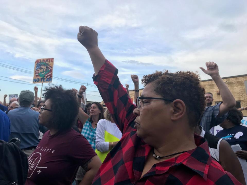 Demonstrators gather outside the Elizabeth immigration detention center on July 2, 2019 as part of nationwide "Close the Camps" events.  They raise their arm as airplanes fly overhead to show their solidarity with immigration detainees.