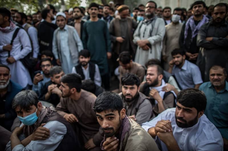 Afghan men wait outside a bank to withdraw money. The sharp reduction in foreign assistance to Afghanistan since the Taliban's return to power in 2021 has severely harmed the country’s healthcare system, Human Rights Watch said in a report on Monday. Oliver Weiken/dpa