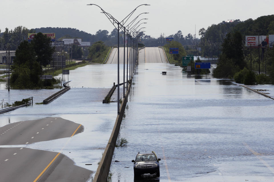 FILE- In this Monday, Sept. 17, 2018, file photo flooded vehicles sit on a closed section of Interstate 95 in Lumberton, N.C., where the Lumber river overflowed following flooding from Hurricane Florence. Navigation apps like Waze are trying to help motorists avoid hurricane flooding, but local authorities say people shouldn’t rely on them. (AP Photo/Gerry Broome, File)