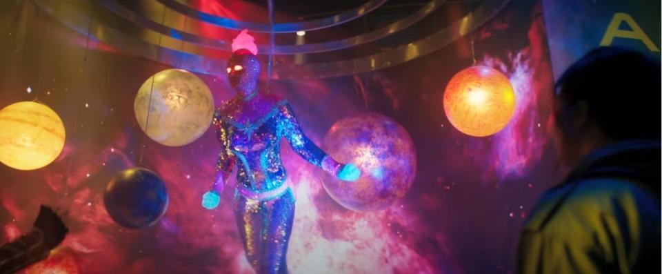 A glowing replica of Captain Marvel surrounded by planets and galaxy projections at a fan event