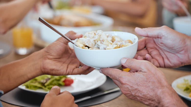 Hands passing potato salad 