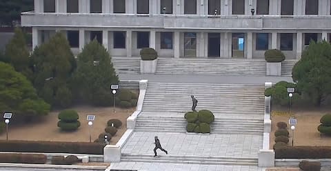 North Korea soldiers, at a landmark known to the thousands of tourists who visit the border, react to the news of a defection from Panmungok - Credit: AFP