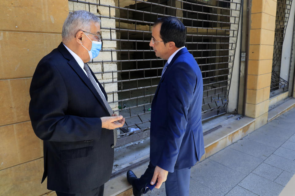 Cyprus Foreign Minister Nikos Christodoulides, right, speaks with his Lebanese counterpart Abdullah Bou Habib, as they stand in front a shop that was damaged by the massive seaport explosion last year, in Beirut, Lebanon, Wednesday, Oct. 6, 2021. Christodoulides who is in Beirut for two days visit to meet with Lebanese officials, called on the Lebanese government to implement reforms quickly in order for the international community to unlock aid for Lebanon that is witnessing one of the worst economic crises in the world in decades. (AP Photo/Hussein Malla)