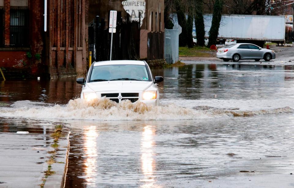 PHOTO: A car drives through a flooded street after a large rainstorm, Dec. 18, 2023, in Paterson, N.J. (Kena Betancur/Getty Images)