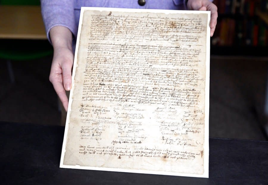 A collections associate with the Connecticut Historical Society displays a 1669 complaint against a woman who was tried multiple times for witchcraft, the Associated Press reported. One of the complaints, according to the letter, blamed her giving headaches to someone who wore a hat she had wanted to purchase. (AP Photo/Jessica Hill)