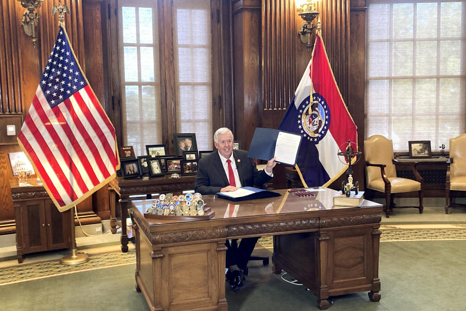 Missouri Gov. Mike Parson holds up legislation cutting the state’s income tax rate after signing it into law Wednesday, Oct. 5, 2022, at his Capitol office in Jefferson City, Mo. Parson said the new law would reduce people’s taxes by 5% and cost the state about $760 million when fully phased in over several years. (AP Photo/David A. Lieb)