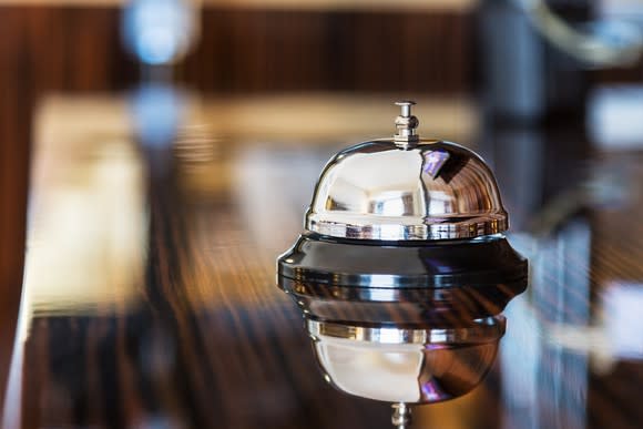 Gleaming service bell on polished wooden hotel lobby desk.