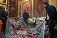 In this Thursday, Feb. 7, 2019 photo, Iranian merchants look at a hand-woven carpet at the Grand Bazaar in Tehran, Iran. The economy faces multiple struggles as the country marks the 40th anniversary of the Islamic Revolution. Inflation continues to rise as its currency depreciates and university graduates are unable to find jobs. Some of the challenges stem from the re-imposition of U.S. sanctions while other problems date back to the time of the revolution. (AP Photo/Vahid Salemi)