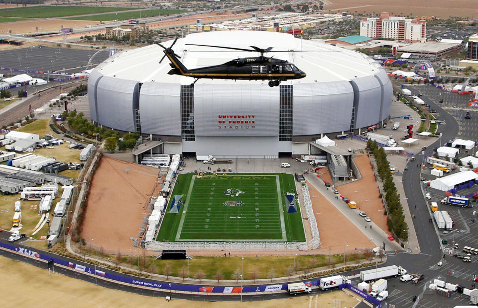 FILE - In this Monday, Jan. 26, 2015, file photo, with the grass field tray outside, a U.S. Customs and Border Protection Black Hawk helicopter circles above University of Phoenix Stadium, site of the NFL Super Bowl XLIX football game, during a security demonstration for the media in Glendale, Ariz. The NFL’s players have made it no secret they prefer playing on natural grass as opposed to synthetic turf. They’ll get their wish in Super Bowl 57. (AP Photo/Ross D. Franklin, File)