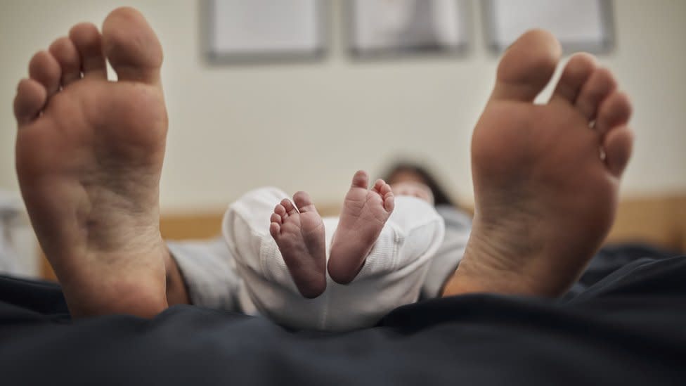 Los pies de un padre junto a los de su bebé recién nacido