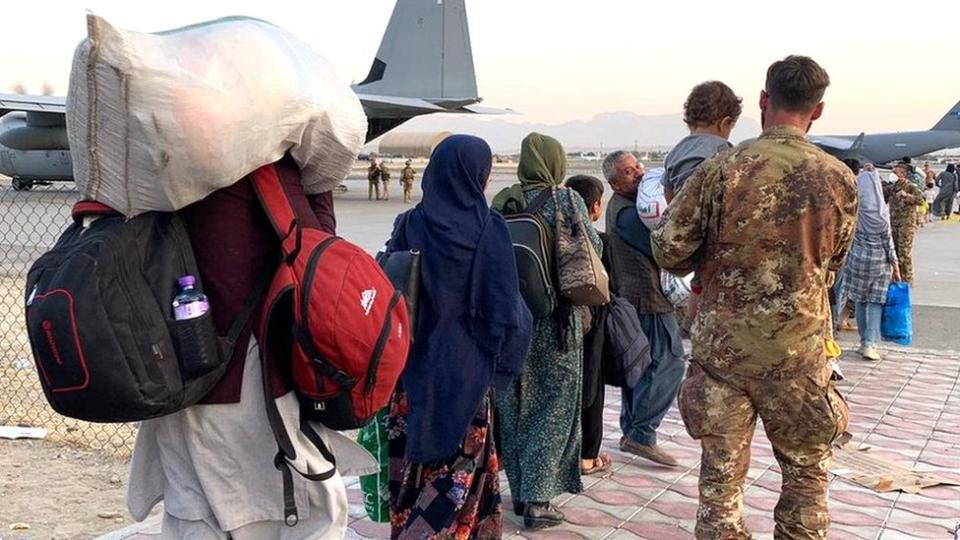 Personas caminando con sus pertenencias en el aeropuerto de Kabul.