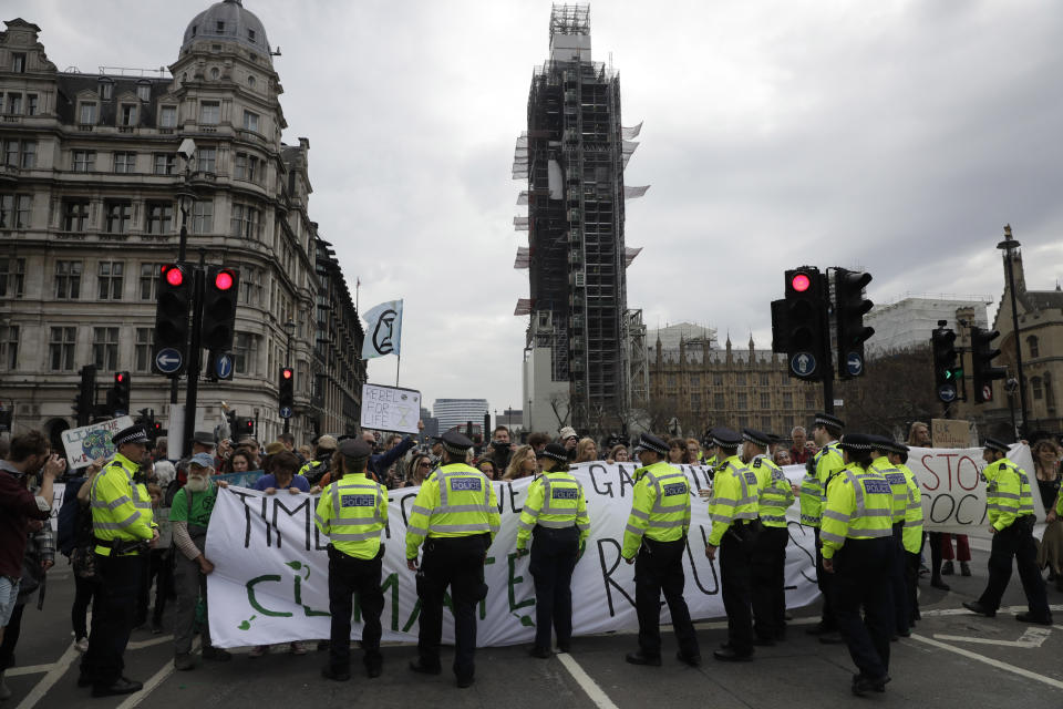 Extinction Rebellion climate change protesters hold banners as they briefly block traffic around Parliament Square, backdropped by the scaffolding covered Big Ben in central London, Wednesday, April 24, 2019. The non-violent protest group, Extinction Rebellion, is seeking negotiations with the government on its demand to make slowing climate change a top priority. (AP Photo/Matt Dunham)