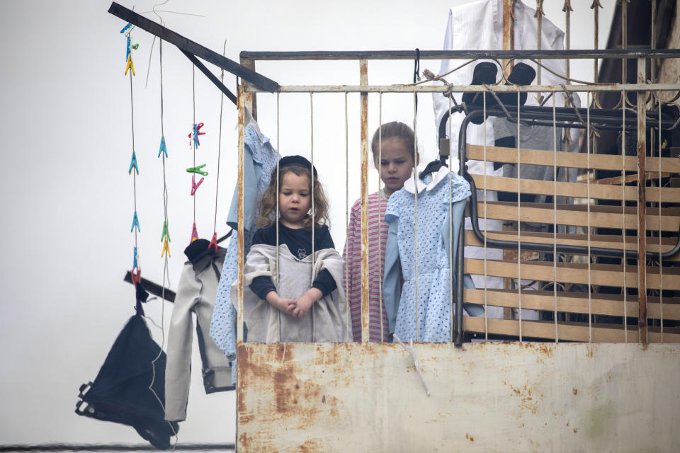 Children watch as leavened items burn in a garbage bin in final preparation for the Passover holiday in the Orthodox neighborhood of Mea Shearim in Jerusalem, Wednesday, April 8, 2020. Israeli Prime Minister Benjamin Netanyahu announced Monday a complete lockdown over the upcoming Passover holiday to control the country's coronavirus outbreak, but offered citizens some hope by saying he expects to lift widespread restrictions after the week-long festival. Passover begins on sundown Wednesday. (AP Photo/Ariel Schalit)