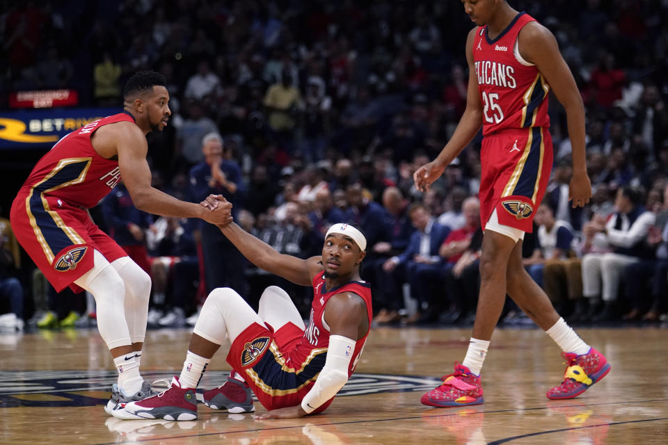 New Orleans Pelicans guard Devonte' Graham is helped up from the court by guards CJ McCollum, left, and Trey Murphy III (25) in the second half of an NBA basketball game against the Dallas Mavericks in New Orleans, Tuesday, Oct. 25, 2022. The Pelicans won 113-111. (AP Photo/Gerald Herbert)