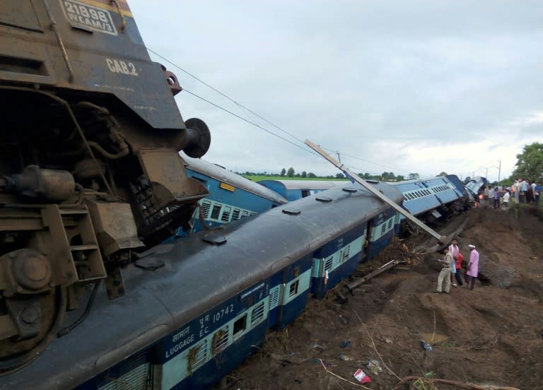 Officials stand next to two passenger trains on top of each other following a derailment after they were hit by flash floods on a bridge outside the town of Harda in Madhya Pradesh state, central India on August 5, 2015