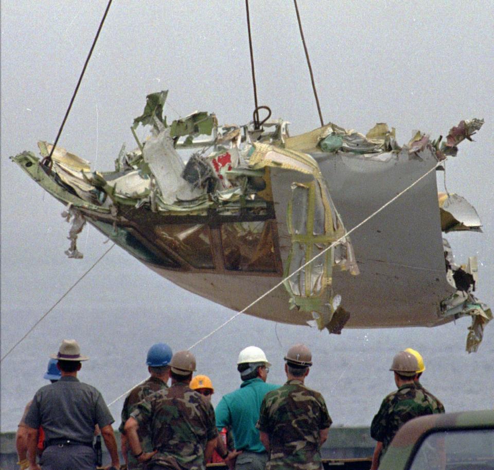 FILE - In this Aug. 7, 1996 file photo, the cockpit of TWA Flight 800 is lowered at the U.S. Coast Guard station at Shinnecock Inlet in Hampton Bays, N.Y. Former investigators on Wednesday, June 19, 2013 called on the National Transportation Safety Board to re-examine the cause, saying new evidence points to the often-discounted theory that a missile strike may have downed the jumbo jet. (AP Photo/Jim Cole, File)