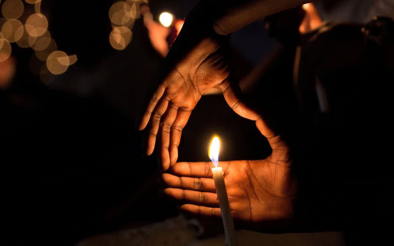 FILE PHOTO: FILE PHOTO: A participant gestures near a night vigil candle during a commemoration ceremony marking the 25th anniversary of the Rwandan genocide, at the Amahoro stadium in Kigali